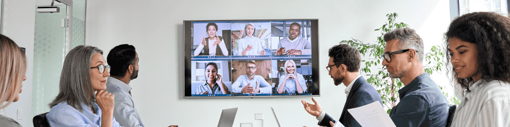 Team of employees gather for in-person amd virtual meeting